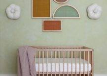 green wall nursery with crib and geometric modern wall art shapes purple blanket