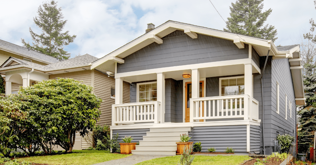 Grey Craftsman style house with stairs leading up to its front porch and entrance door.